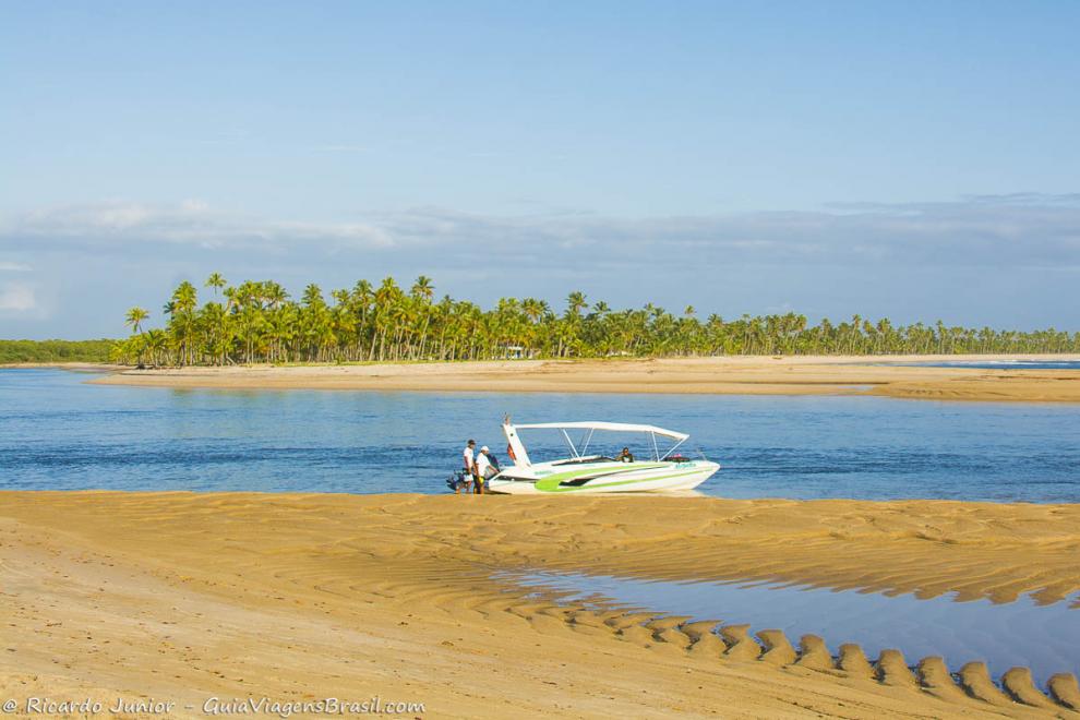 Imagem de banco de areia e uma lancha na Praia da Boca da Barra.